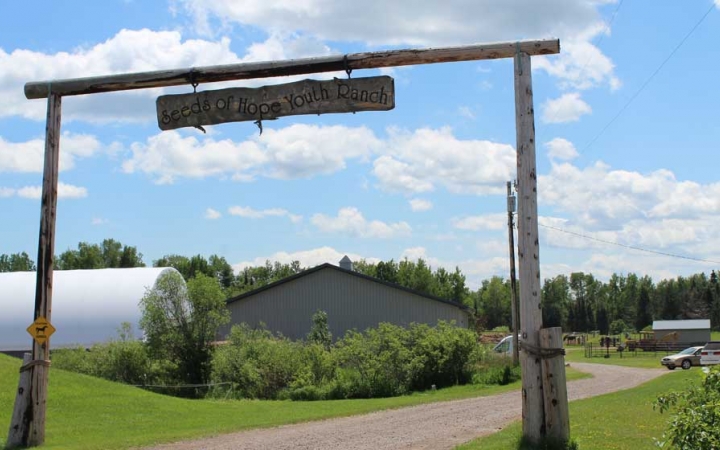 The entrance to an assumed ranch stands before some buildings in the background. 